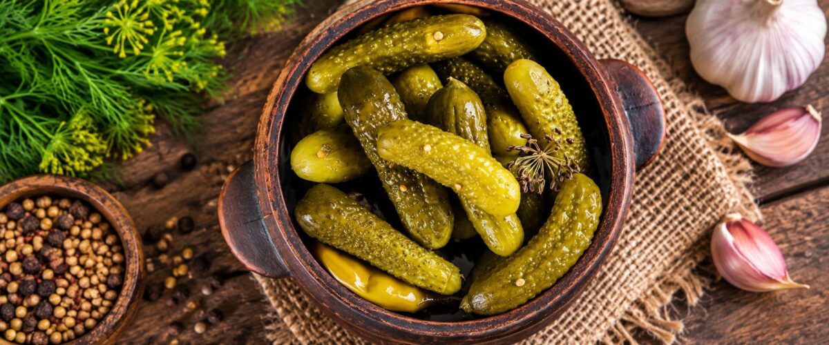 Pickled gherkins in a rustic bowl with dill, garlic, and pickling spices